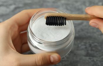 Person with a toothbrush and a jar of soda.