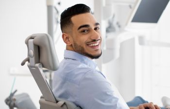 A satisfied young man in a dental chair showing his nice teeth in a smile.