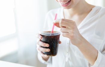 A woman using straw to drink her beverage