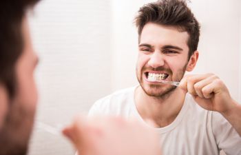 Man brushing his teeth in front of a mirror