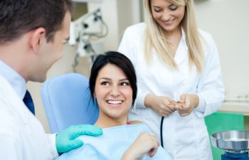 A dentist and his assistant talking to a relaxed cheerful in a dental chair