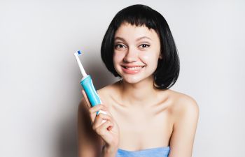 cheerful girl about to brush her teeth with an electronic toothbrush